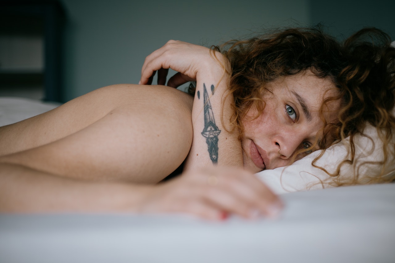 Kobieta z małym tatuażem lezy na łóżku